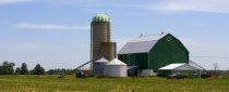 A barn shed with all grain silo storage sitting on top of a large farm field